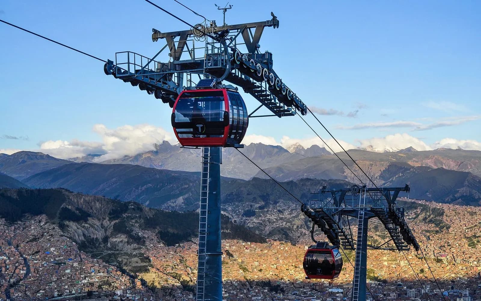 A red Mi Teleférico cable car gondola above the hillside houses of La Paz, Bolivia
