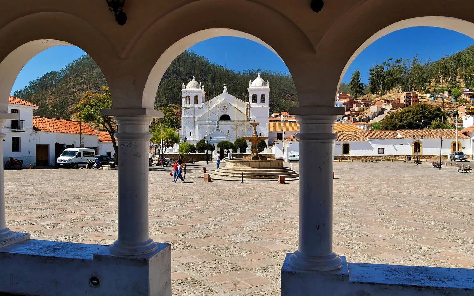 Whitewashed church seen through colonial arches across the cobbled Recoleta square, Sucre, Bolivia