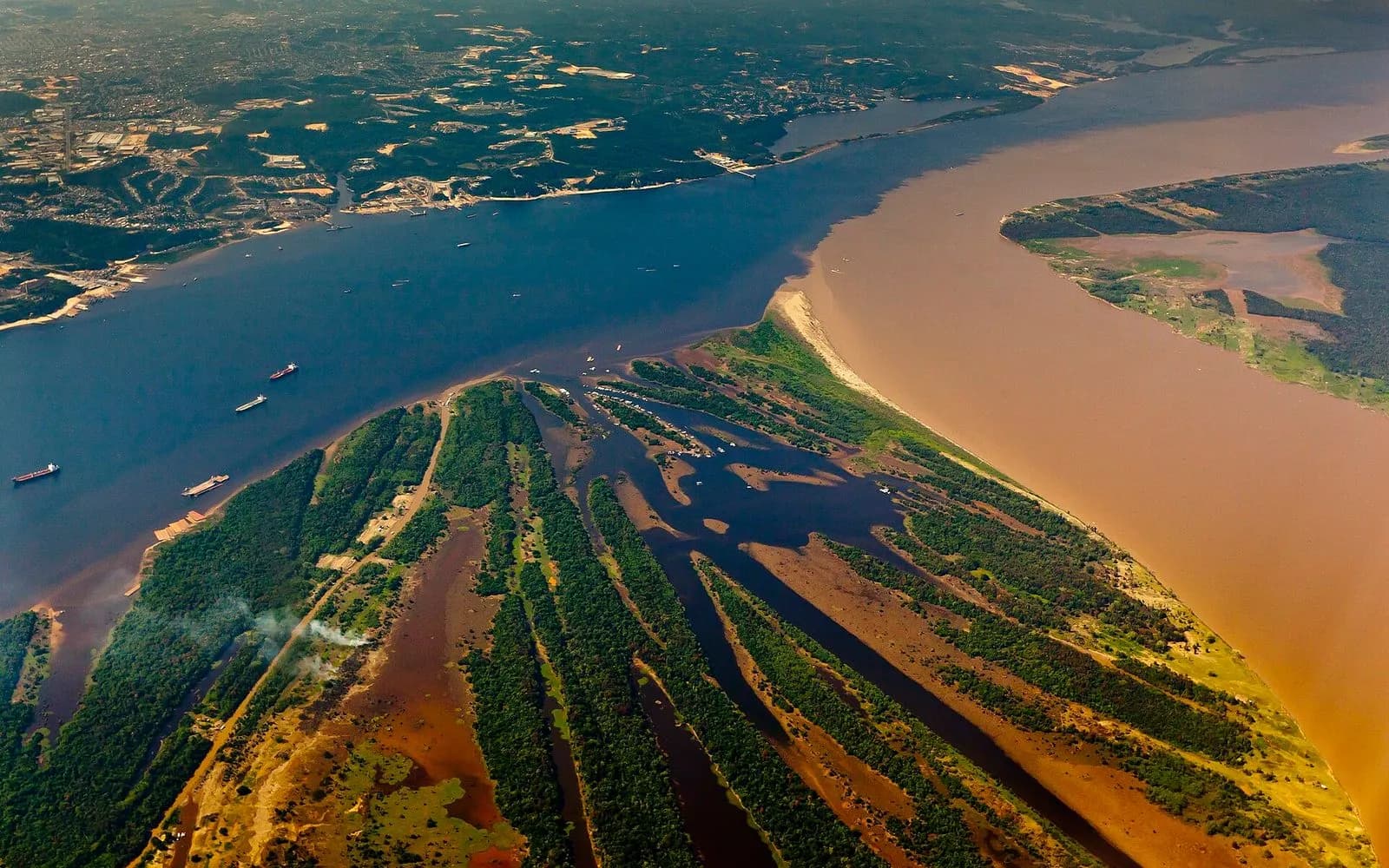 Aerial view of the dark Rio Negro meeting the sandy Solimões river beside Manaus, Amazon, Brazil