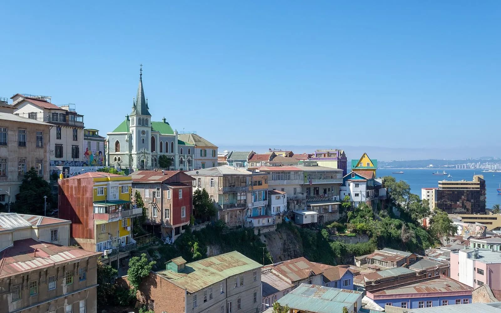 Colourful hillside houses and a green-spired church above the bay on Cerro Concepción, Valparaíso, Chile