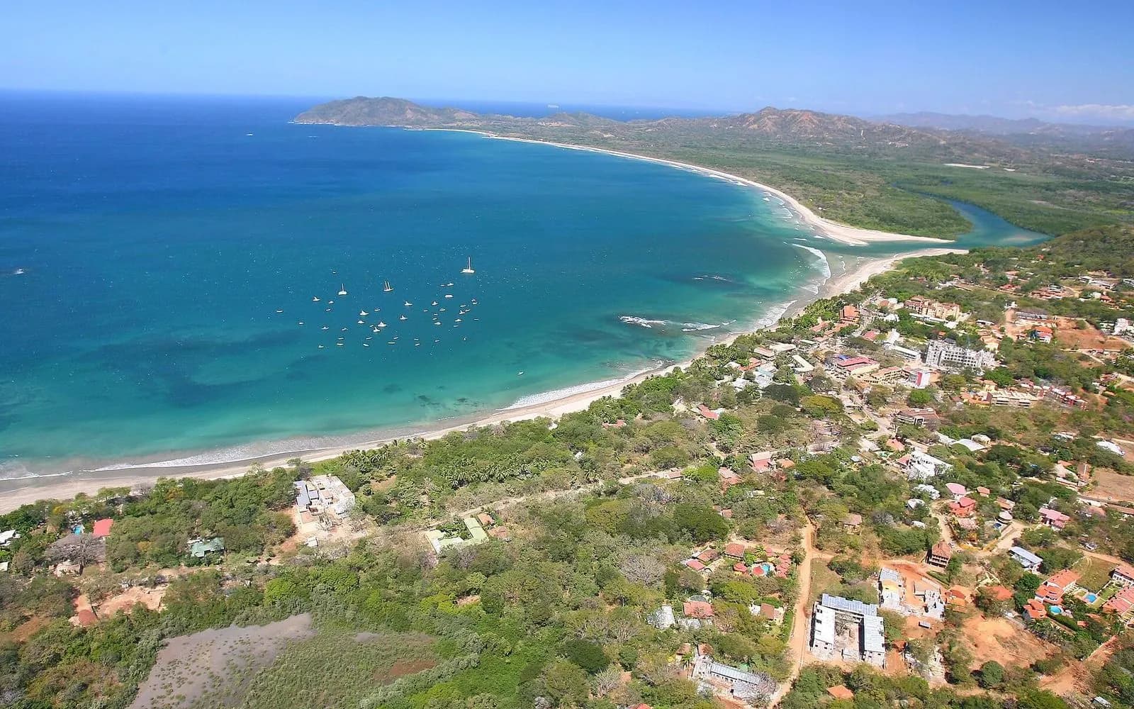 Aerial view of the curving turquoise bay and long beach at Tamarindo, Guanacaste coast, Costa Rica