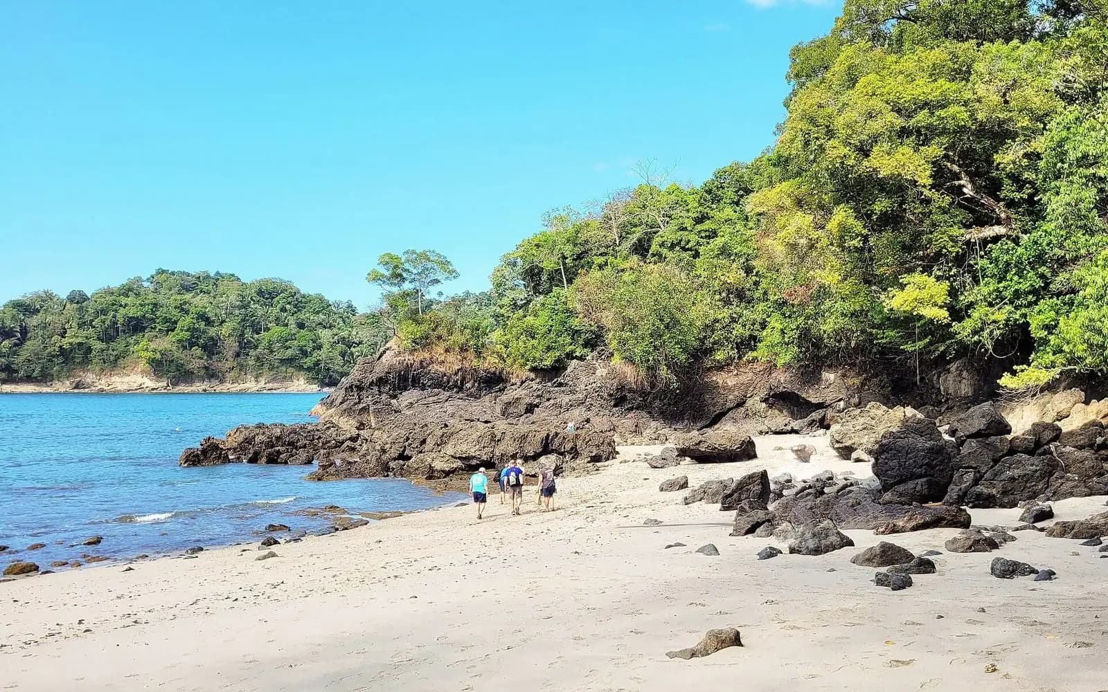 White-sand cove with dark rocks and forested headland, Manuel Antonio National Park, Costa Rica