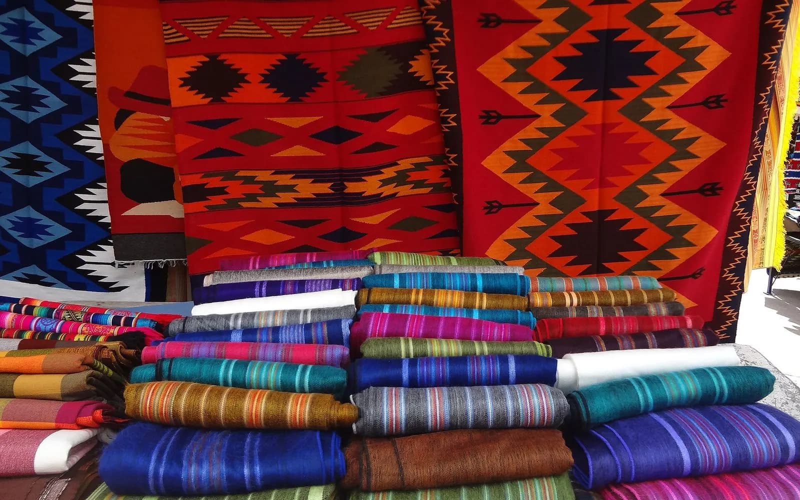 Stacks of striped woollen blankets and woven rugs at the artisan market, Otavalo, Ecuador
