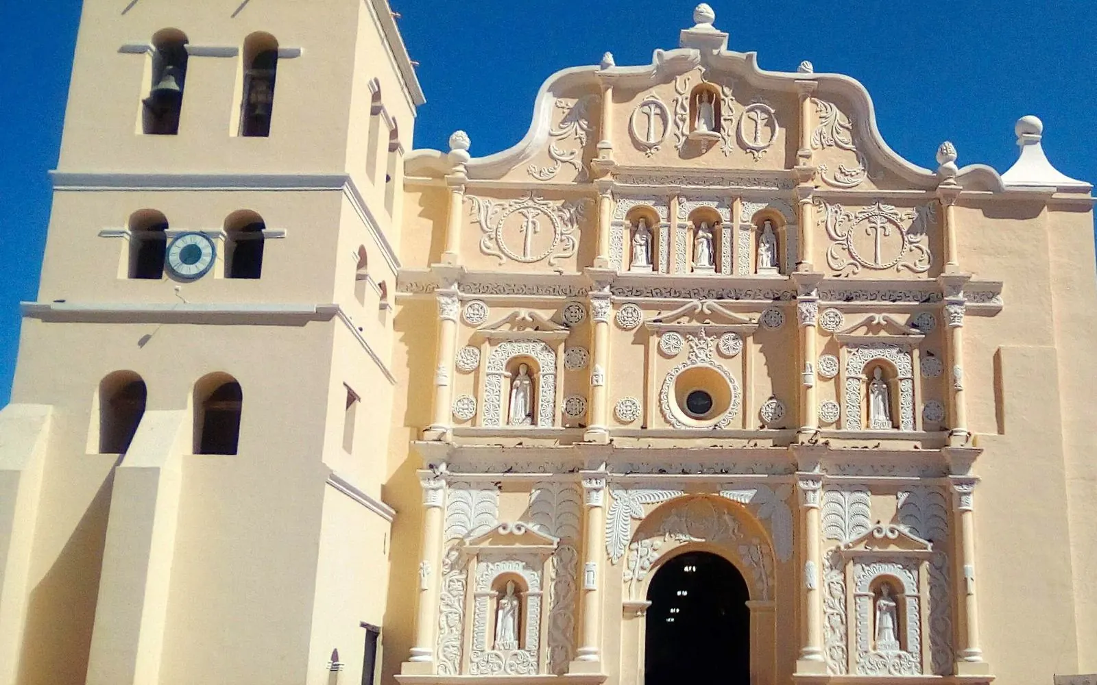 The ornate cream-coloured colonial cathedral facade and bell tower under a deep blue sky, Comayagua, Honduras