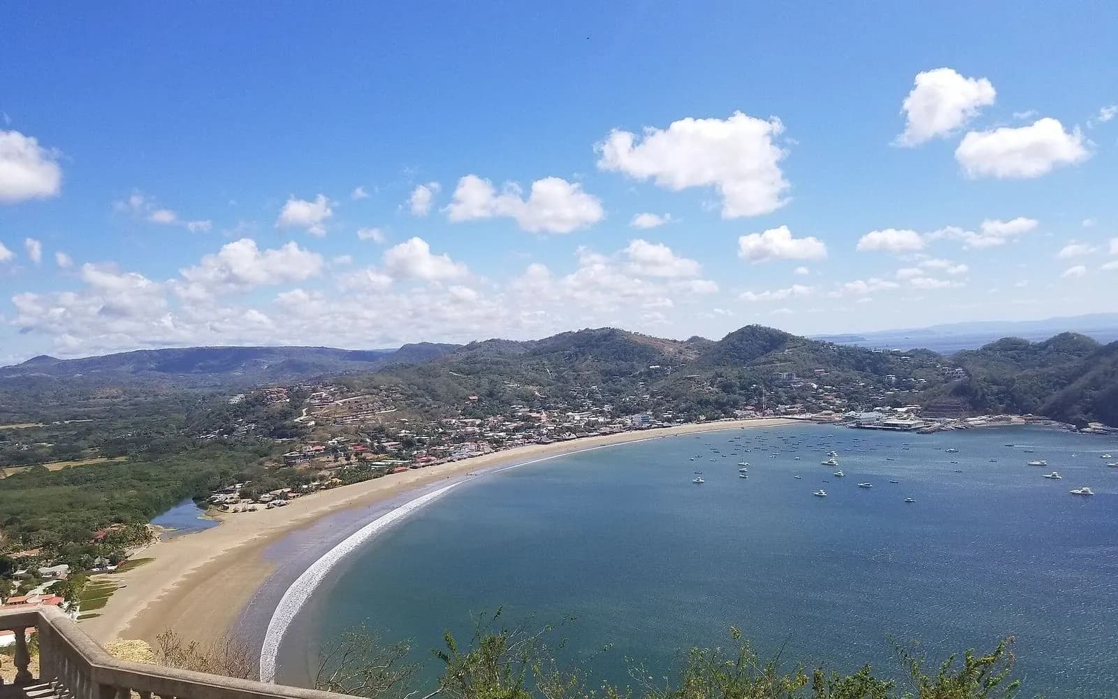 Curving beach and blue bay below green hills, San Juan del Sur, Nicaragua