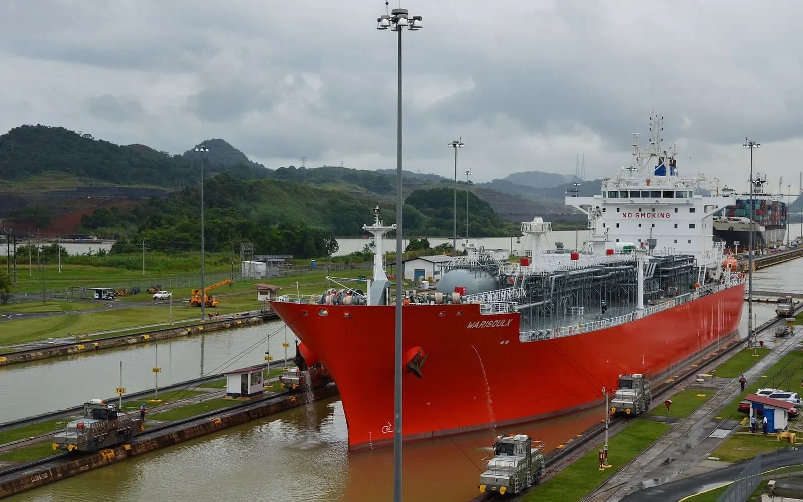 A red tanker passing through the Miraflores Locks with green hills behind, Panama Canal, Panama