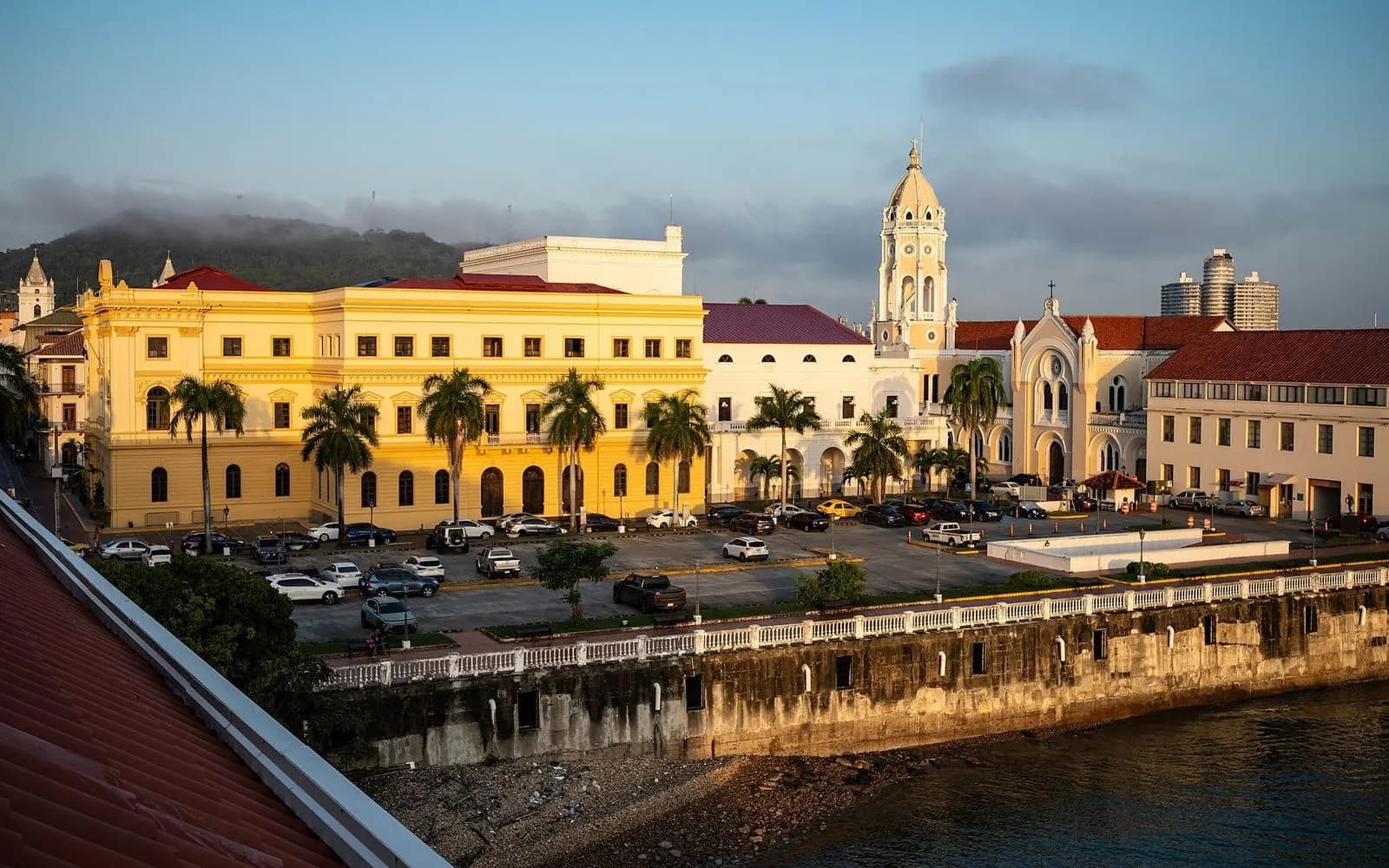Golden light on colonial buildings and a church tower by the bay, Casco Viejo, Panama