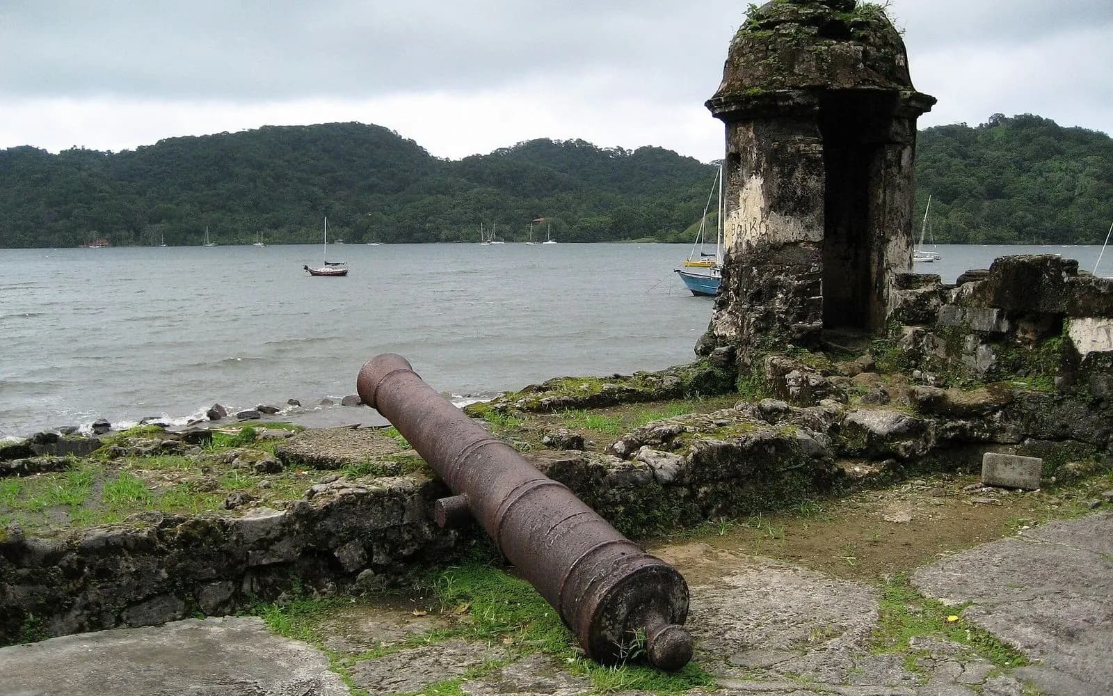 Old iron cannon and stone sentry box overlooking the bay at the Spanish fortifications, Portobelo, Panama