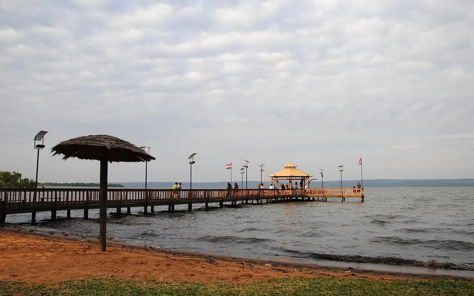 A wooden pier with a thatched shelter reaching into Lake Ypacaraí at Areguá, Paraguay