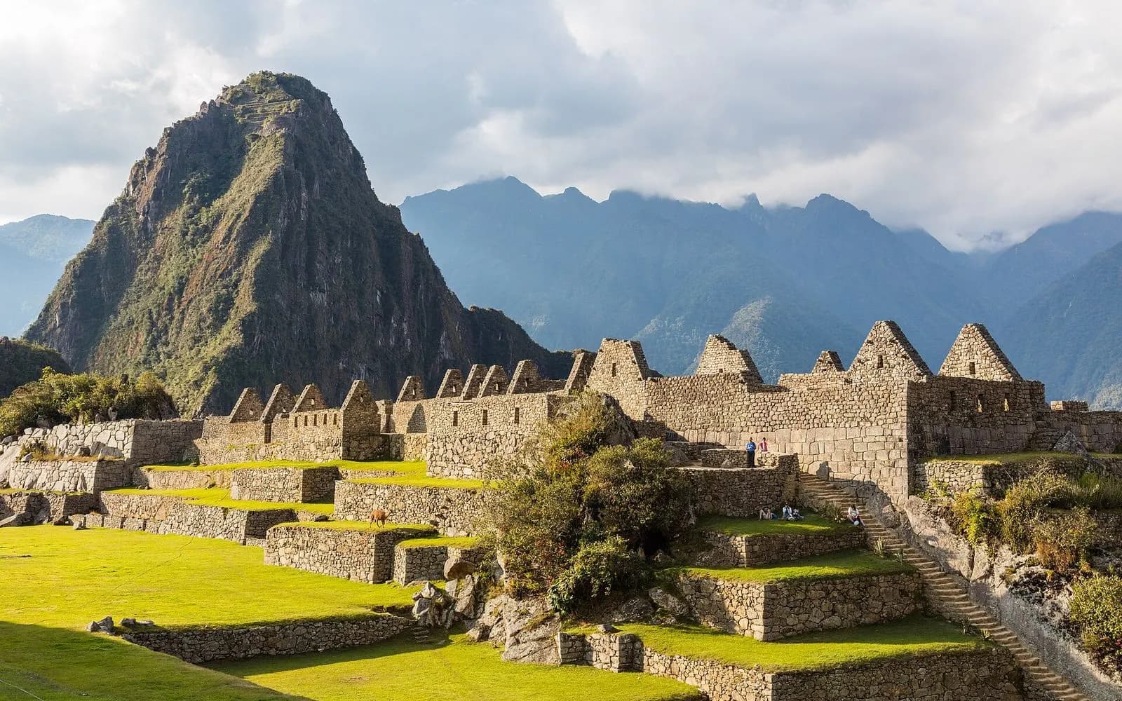 Machu Picchu's terraces and gabled stone houses below Huayna Picchu in warm afternoon light, Peru