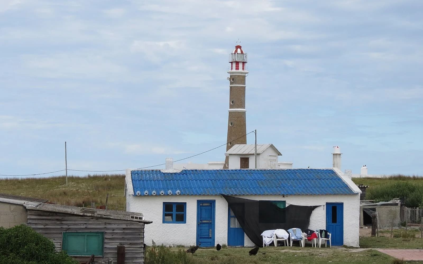 Cabo Polonio lighthouse rising behind a white fishermen's house with a blue tin roof, Rocha, Uruguay